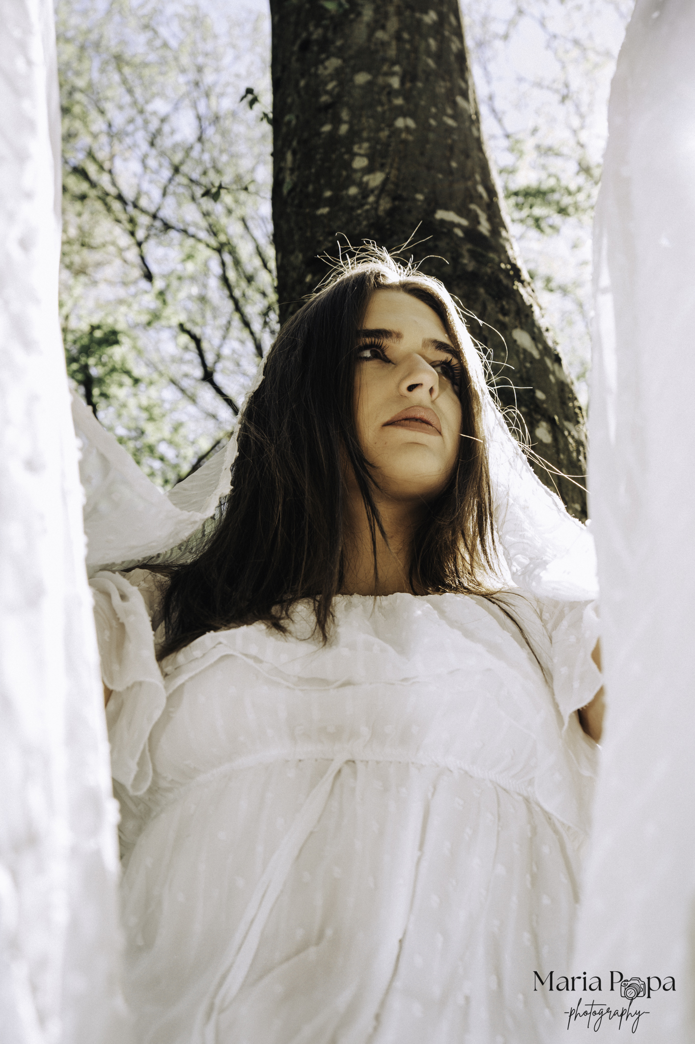 Portret feminin în natură, încadrat de lumină și copaci